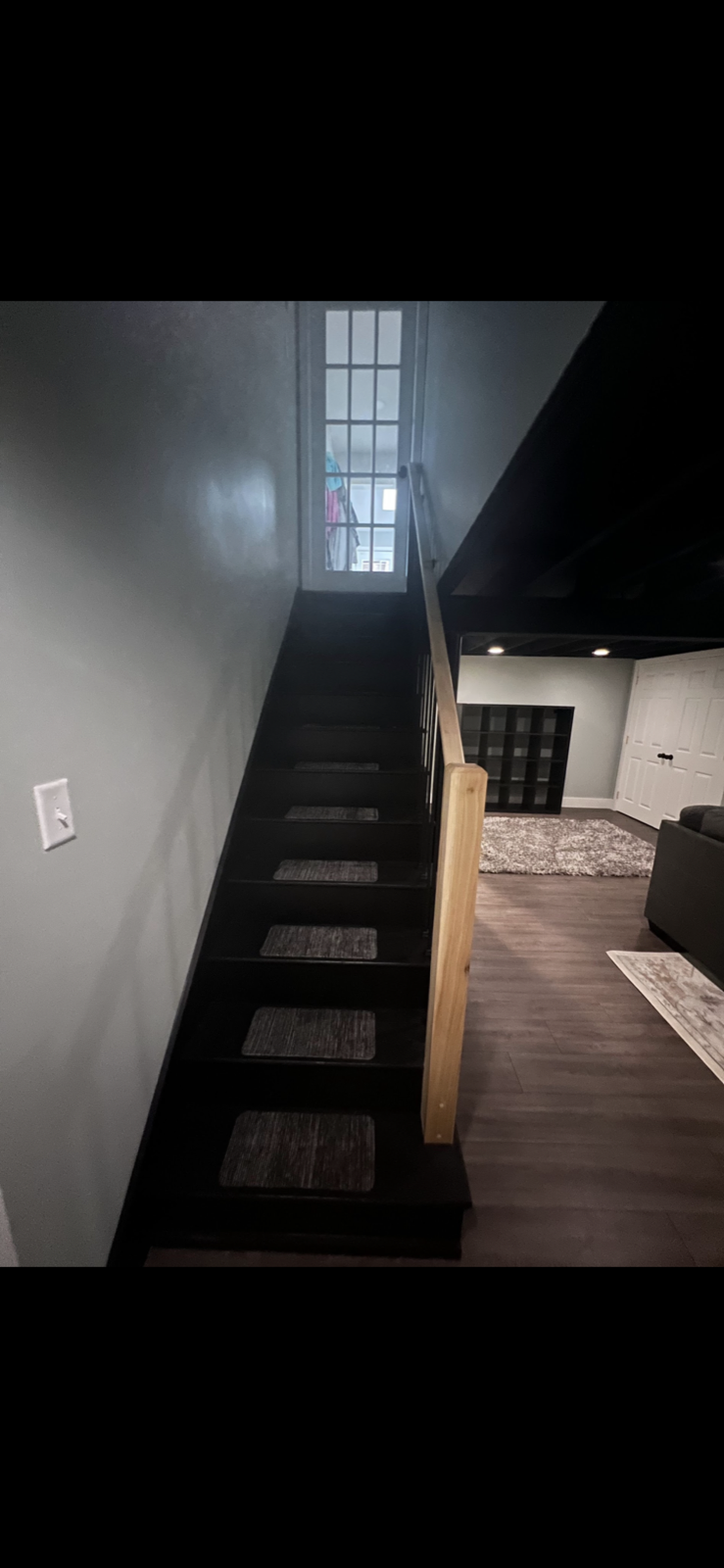Finished basement with dark custom staircase and wood-look flooring